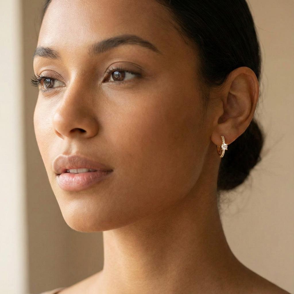 Boucles d’oreilles Huggie « Annelise » en acier inoxydable doré ornées de zircons. Design circulaire raffiné est sublimé par une pierre centrale éclatante et une rangée de petits cristaux pavés