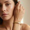 Bracelet jonc « Penelope » en acier inoxydable doré orné de motifs trèfle gravés et de zircon scintillants