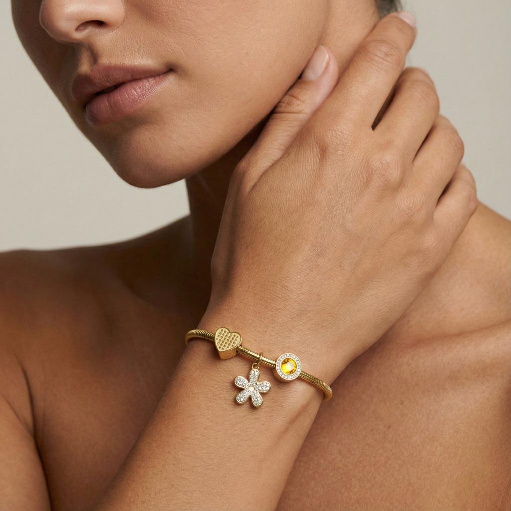 Bracelet maille serpent « Vera » en acier inoxydable doré orné de trois charms élégants un cœur texturé, une fleur incrustée de strass et un médaillon rond avec zircon jaune